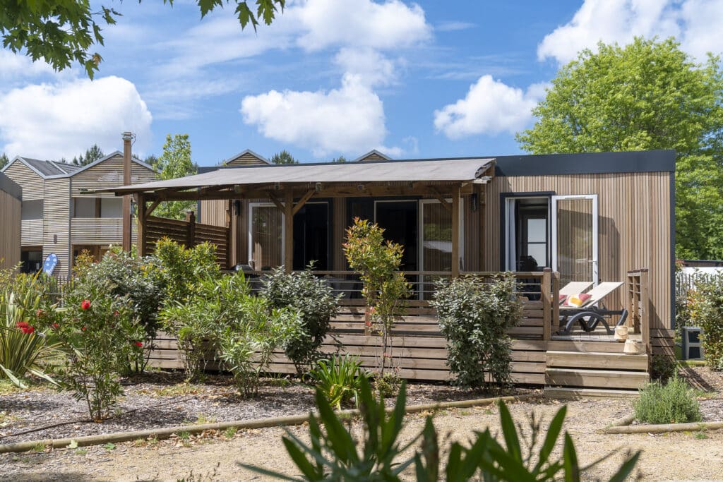 Terrasse en bois avec jardin fleuri, ciel bleu.